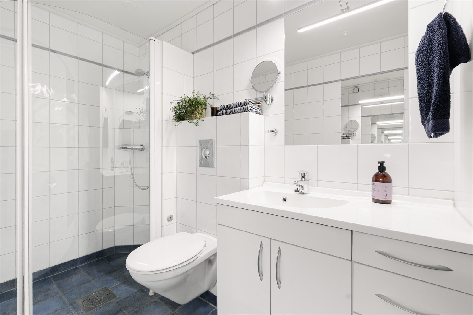 Badet har moderne servantseksjon, speil og dusjhjørne med dører i herdet glass Galleribilde