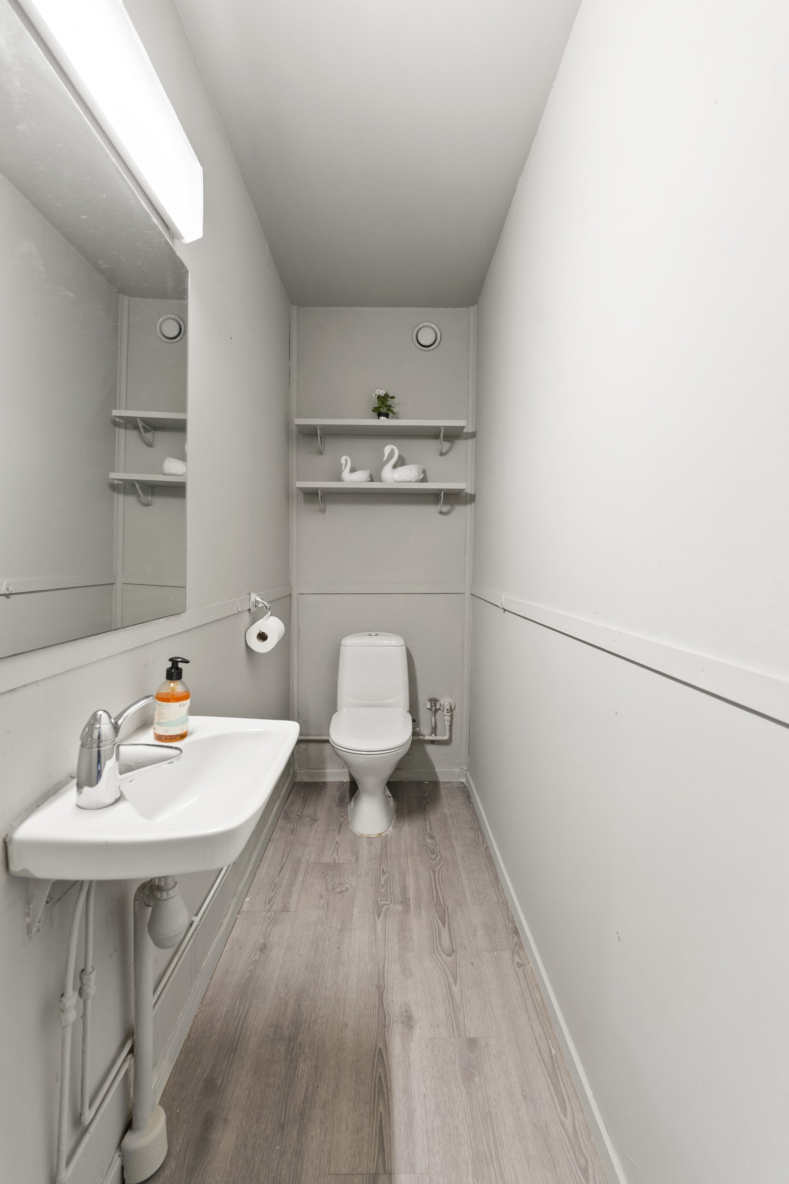 Toalettrom med lamnintgulv og malte veggflater. Rommet har innredning med toalett og servant Galleribilde