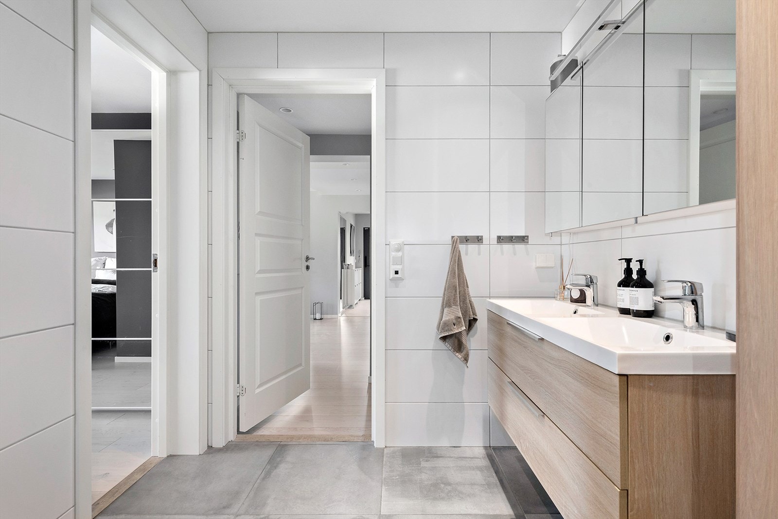 Badet byr på dobbeldusj (regnfalls) med glassvegger, vegghengt toalett, dobbel servant med underskap og stort speilskap med belysning. Galleribilde