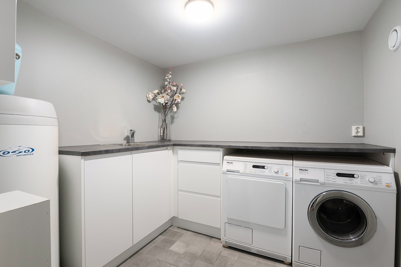 Boligen har eget vaskerom med utslagsvask, godt med skap- og benkeplass og opplegg for vaskemaskin og tørketrommel under praktisk benk. Galleribilde