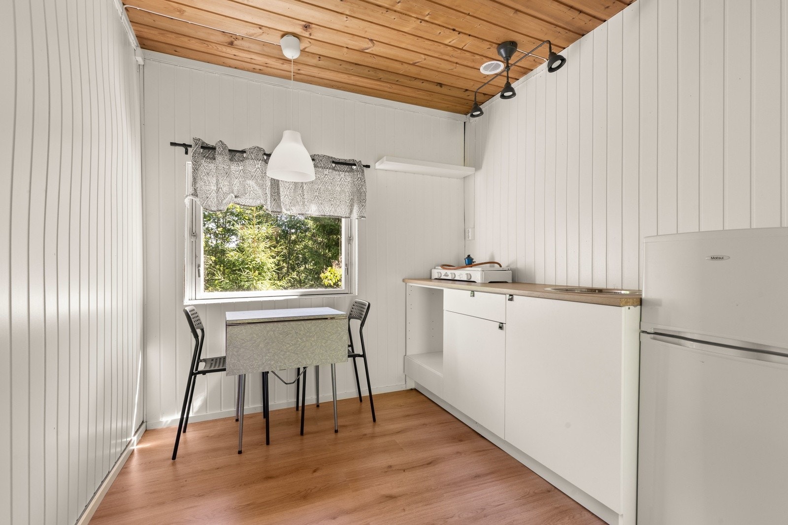 Lite og praktisk kjøkken med benkeplate, vask og plass til kjøleskap og et spisebord. Galleribilde