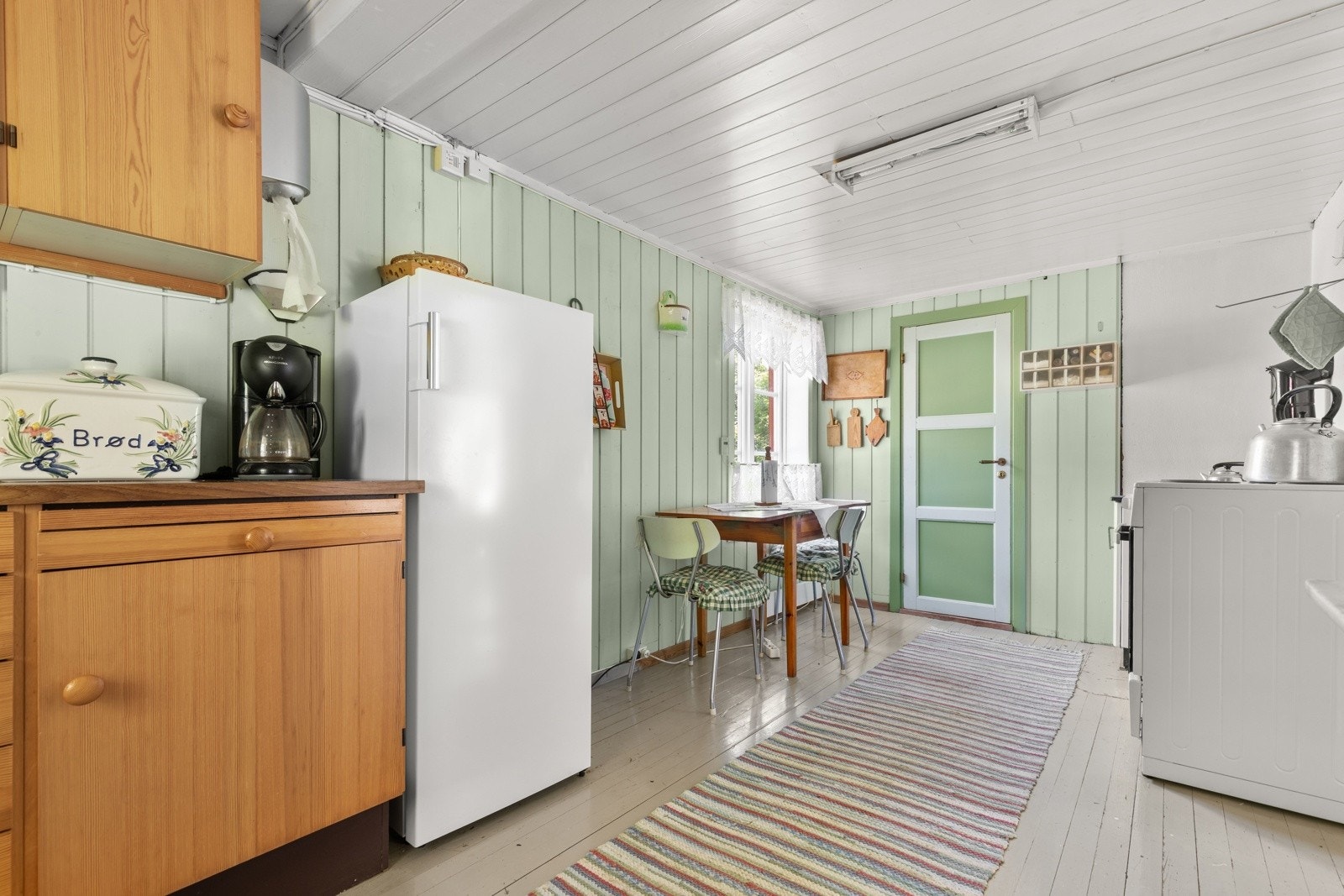 Kjøkkenet har glatte fronter, laminat benkeplate, og plass til både komfyr og kjøleskap. Galleribilde