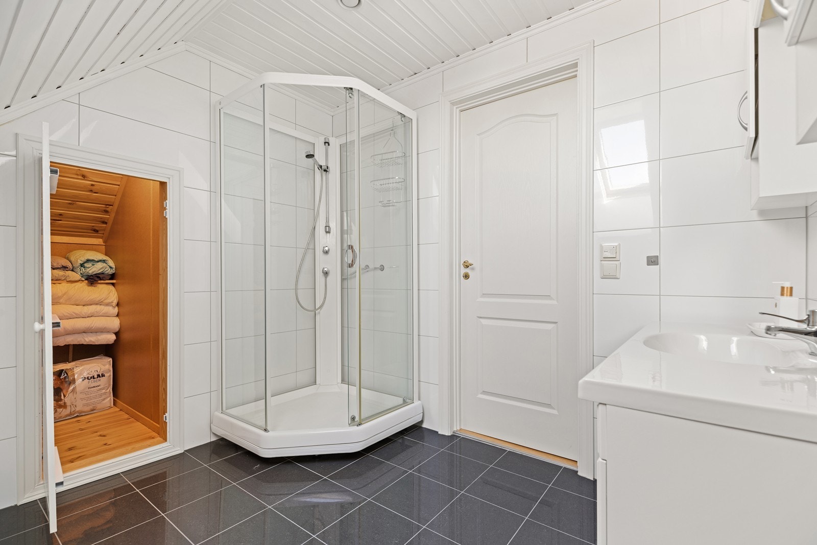 Badet er innredet med nedfelt servant, toalett og dusjkabinett. I tillegg finnes et praktisk kott - ideelt for oppbevaring av dyner og annet du vil ha lett tilgjengelig, men ute av syne Galleribilde