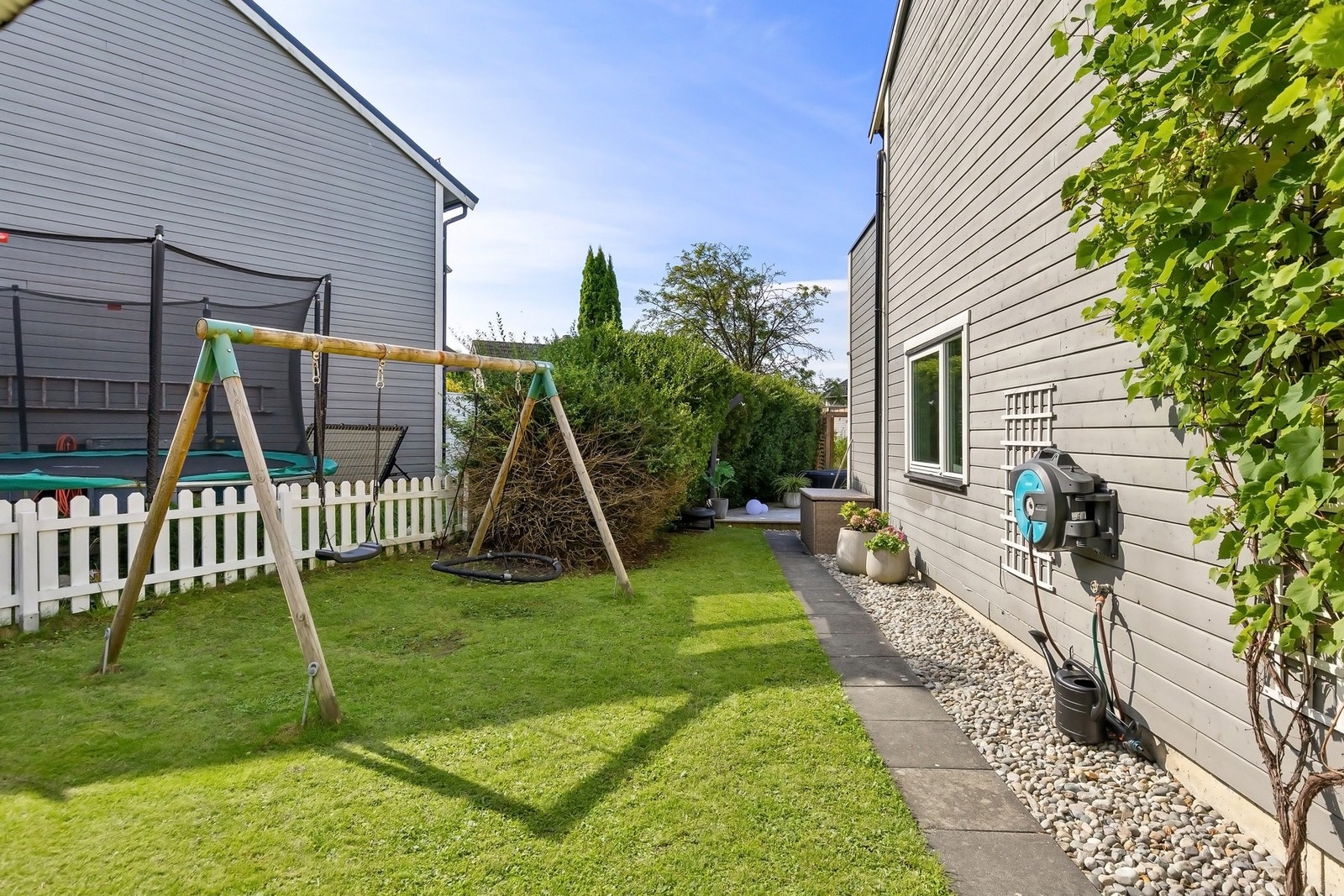 På siden av rekkehuset finner man en fin flat hage med huskestativ Galleribilde