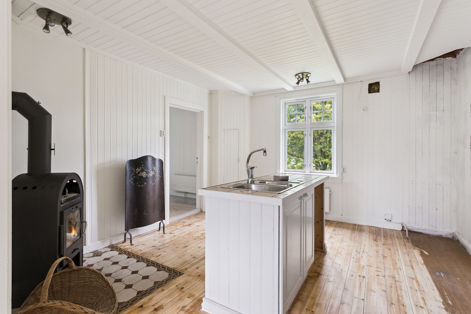 Kjøkkenet har plassbygget kjøkkenøy fra 2004 med flislagt benkeplate og vedovn. Galleribilde