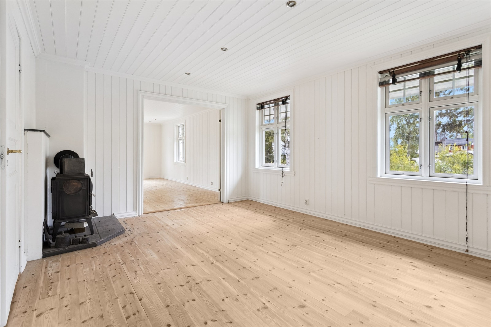 Stue med store vindusflater, vedovn og plass til både sofagruppe og spisebord. Galleribilde