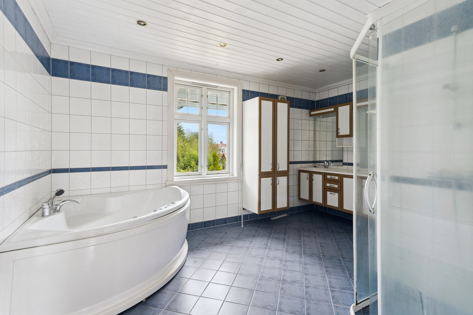 Romslig baderom med fliser på gulv og vegger og opplegg for vaskemaskin. Galleribilde