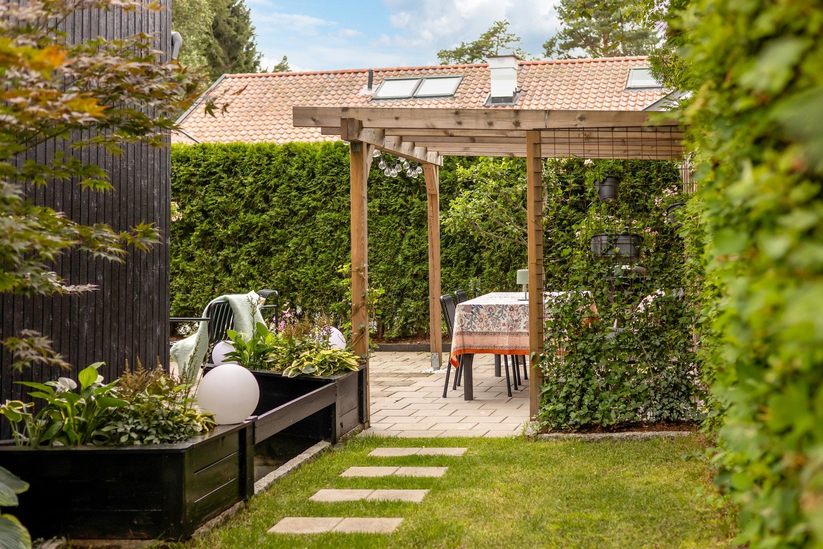 Markise over deler av uteplassen, pergola, gressplen og blomsterbed (steinlagt og oppgradert i 2023). Galleribilde