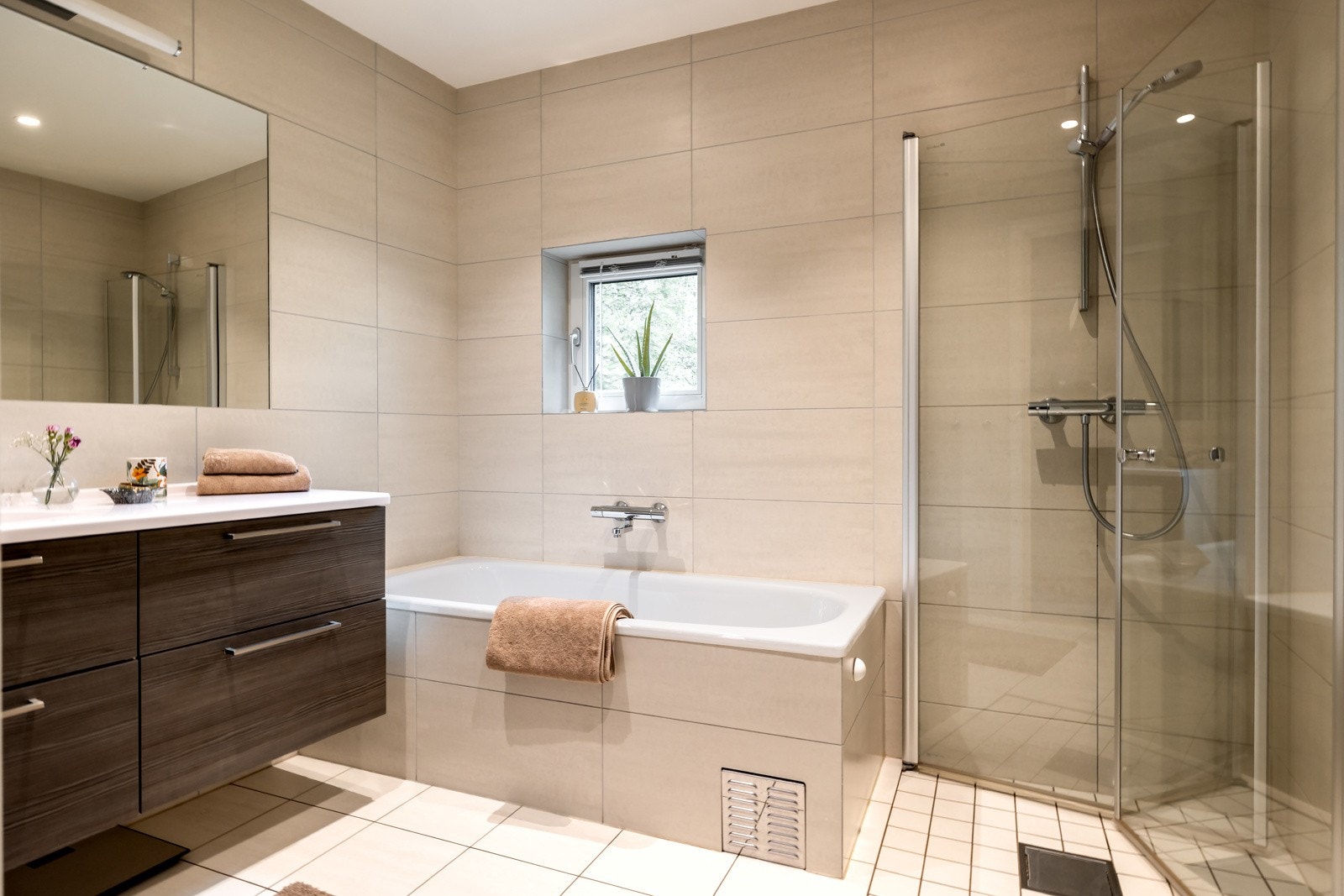 Flislagt bad fra 2015 med innfliset badekar, separat dusj med glassdører, veggmontert toalett og baderomsinnredning Galleribilde