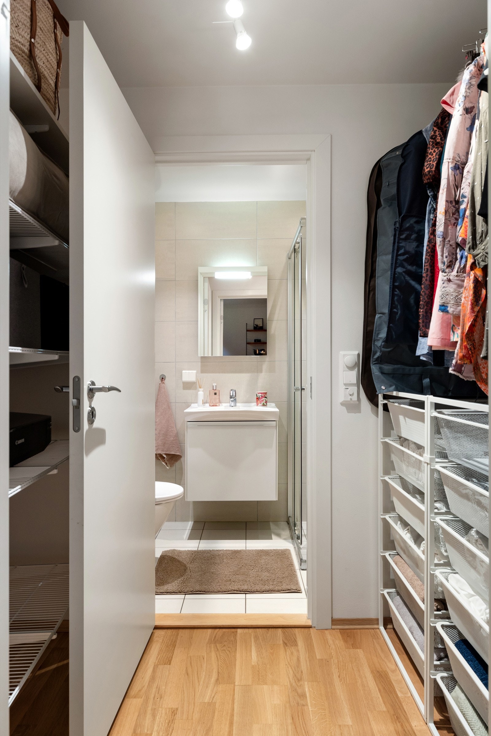 Flere garderobeløsninger og bad med dusjhjørne med glassdører, vegghengt toalett og servantskap. Opplegg for vaskemaskin. Galleribilde