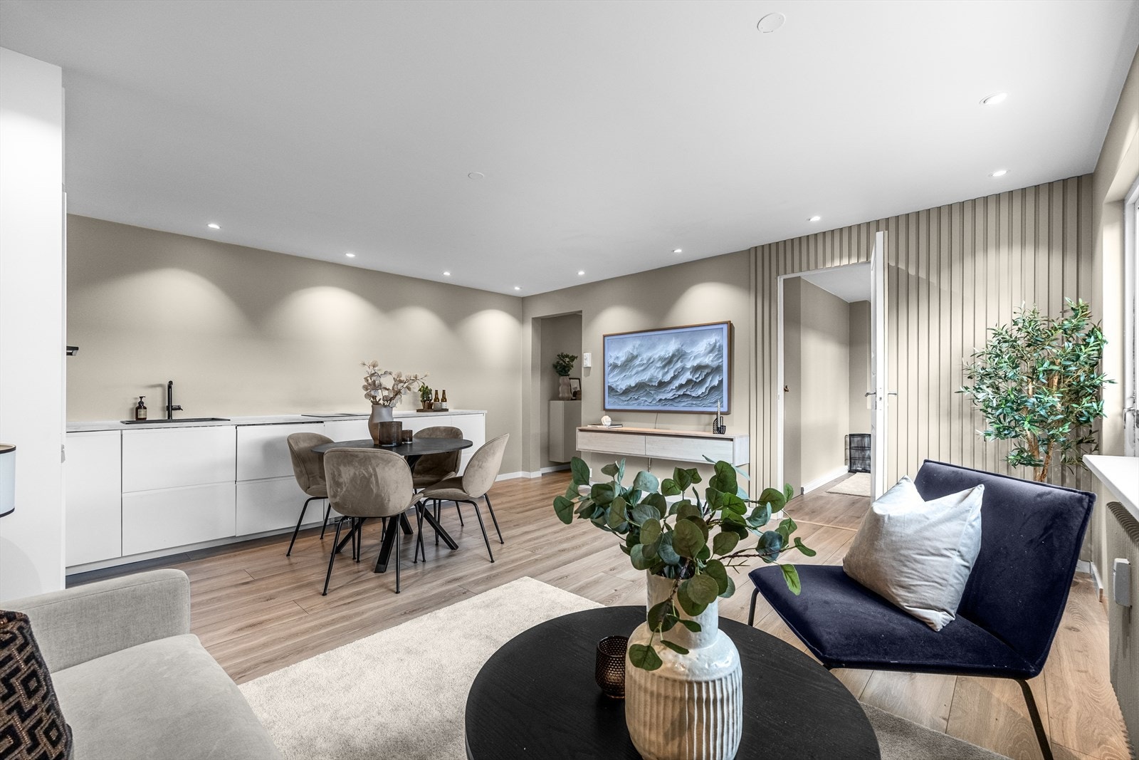 Den åpne løsningen mot det moderne kjøkkenet gir både romfølelse og en sosial sone perfekt for hyggelige sammenkomster. Galleribilde