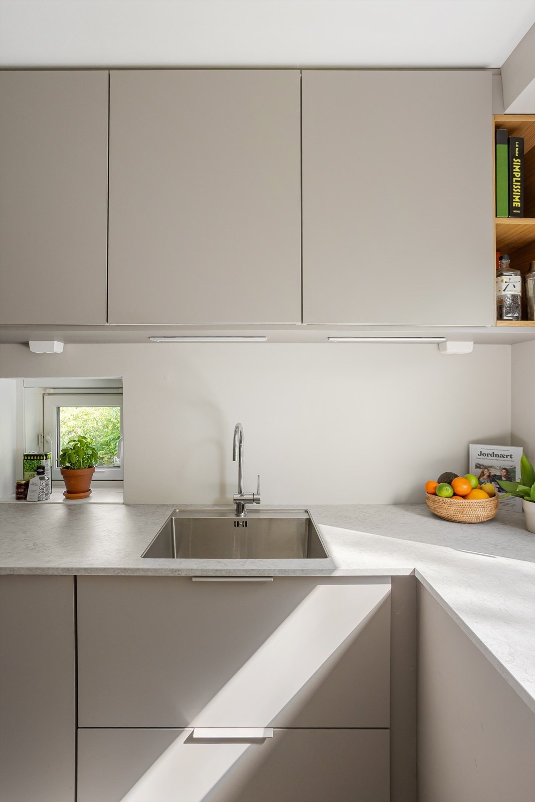 Kjøkkeninnredning med glatte fronter som er utnyttet helt opp til taket. Galleribilde