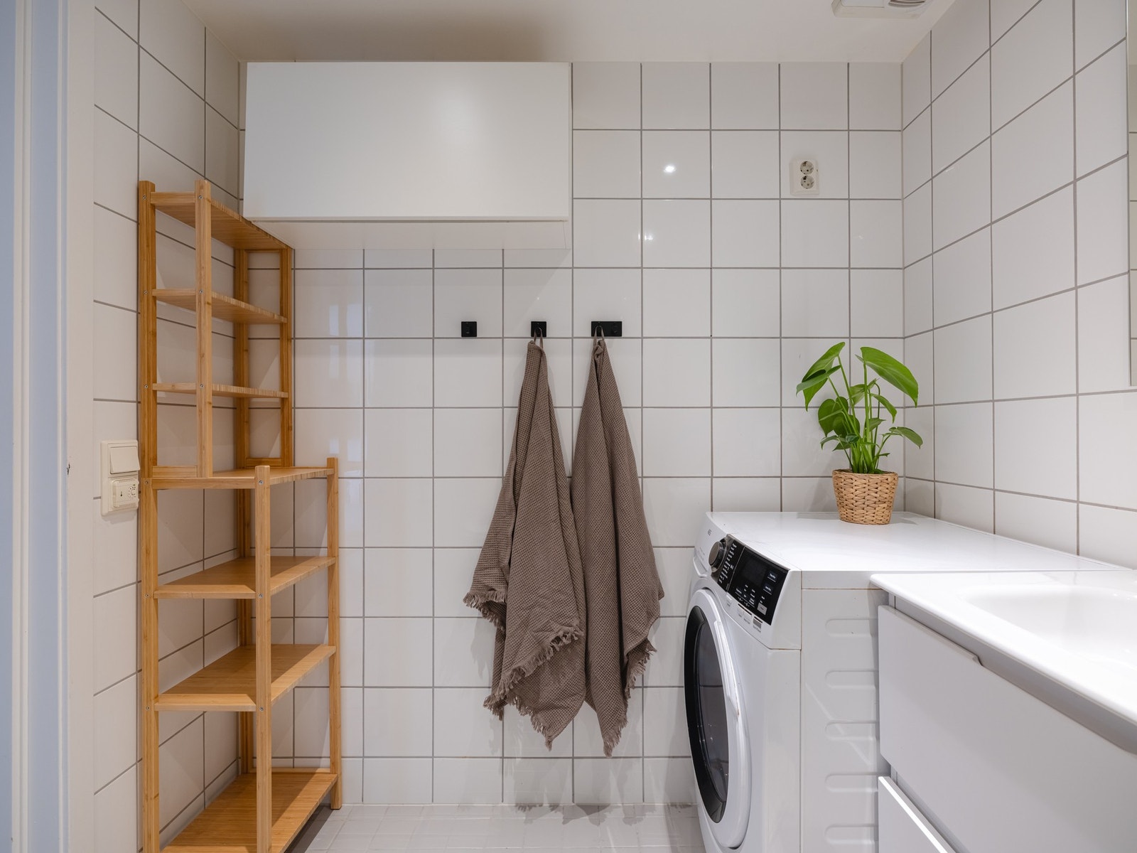 Videre er det dusjhjørne med glassdører til å slå inn og vegghengt toalett. Det er opplegg for vaskemaskin. Galleribilde