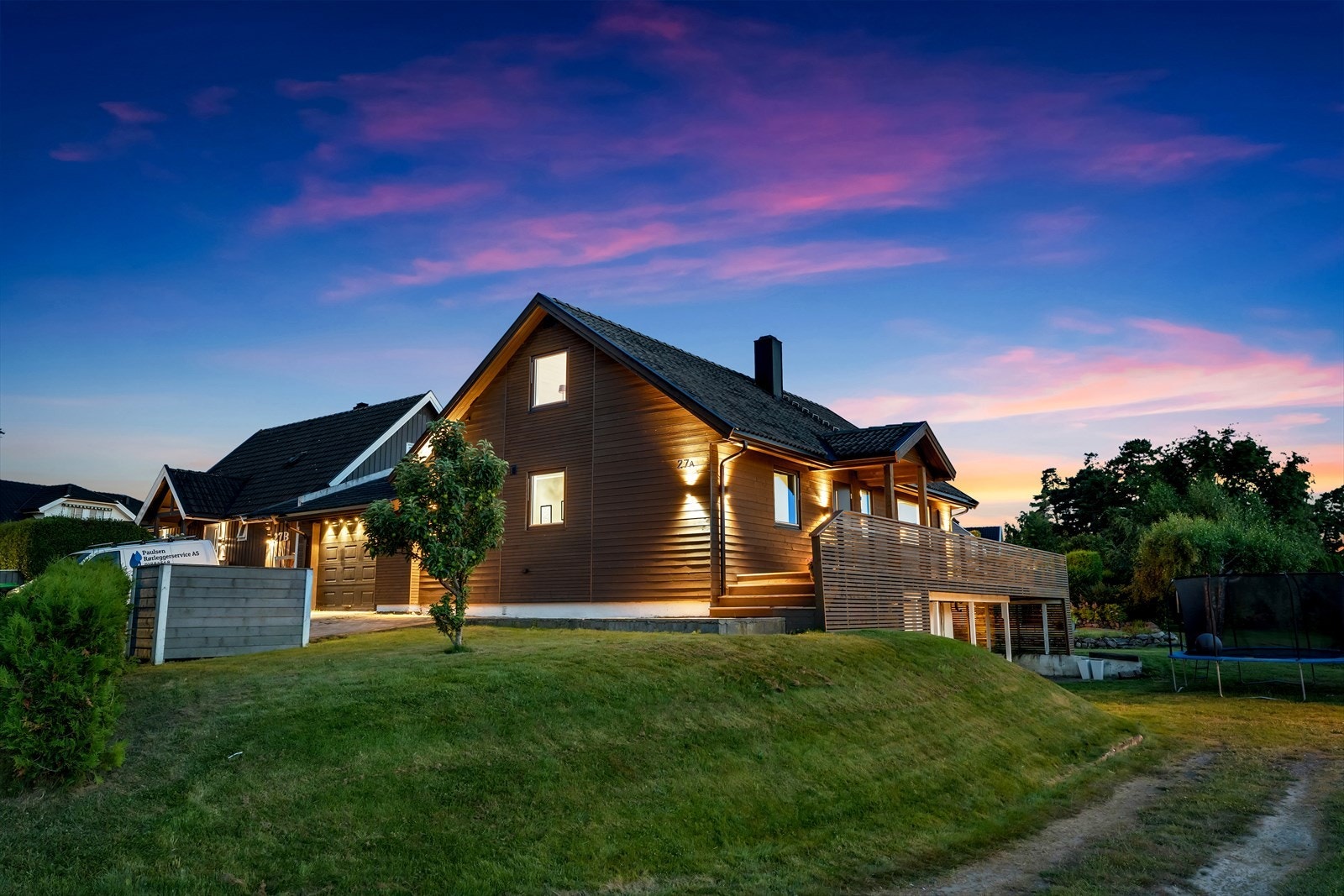Tomten er opparbeidet med belegningsstein ved innkjøring garasje, gressarealer og terrasseplatting/veranda Galleribilde