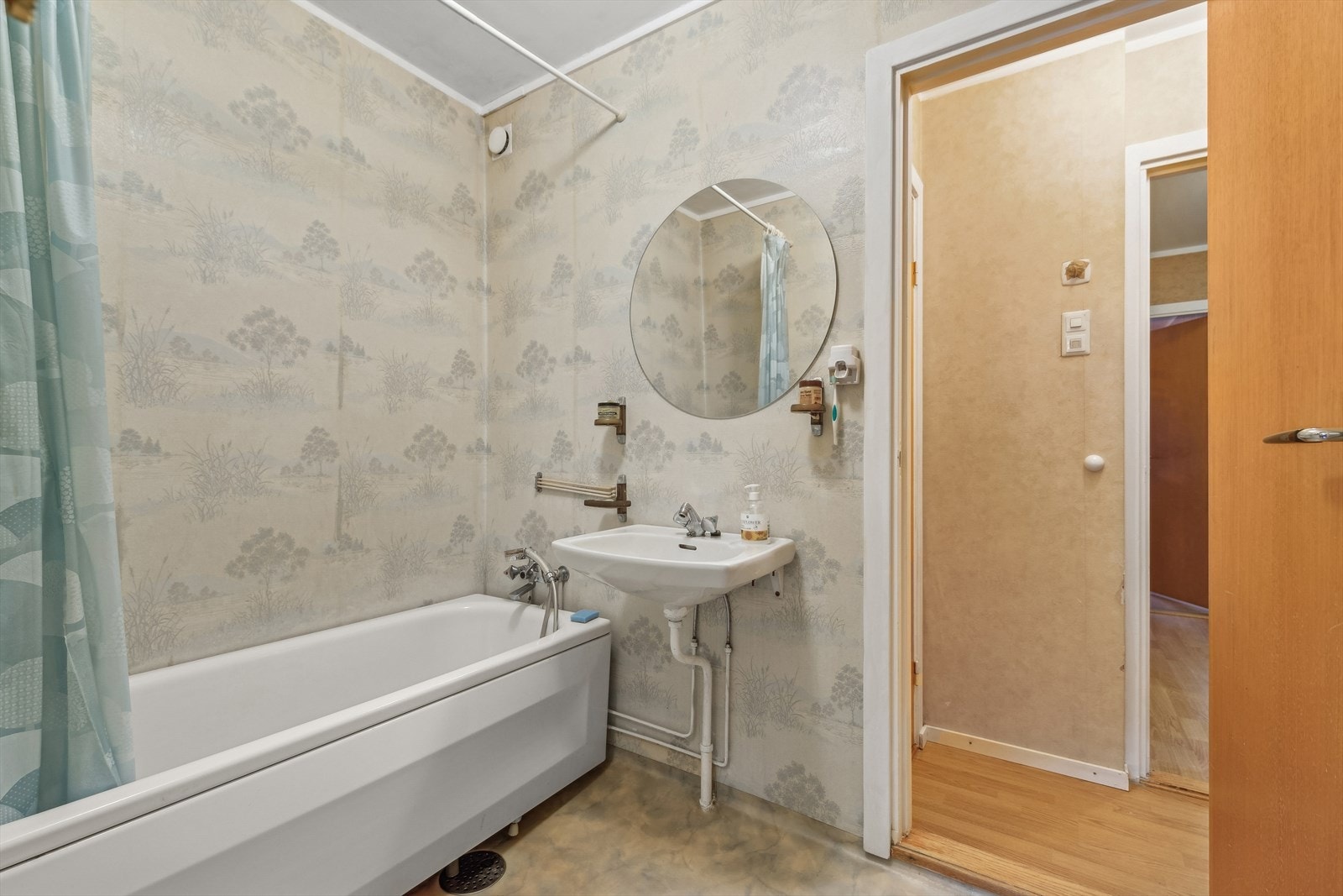 Baderommet har belegg på gulvet og våtromstapet på veggene. Rommet er innredet med servant og badekar Galleribilde