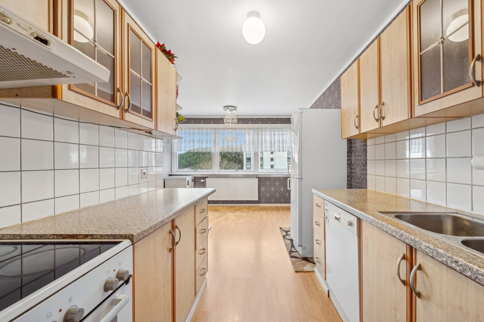 Kjøkkenet har en separat beliggenhet med adkomst fra stue og entré. Rommet har en innredning med glatte fronter, noen glassfronter og benkeplate av laminat. Galleribilde