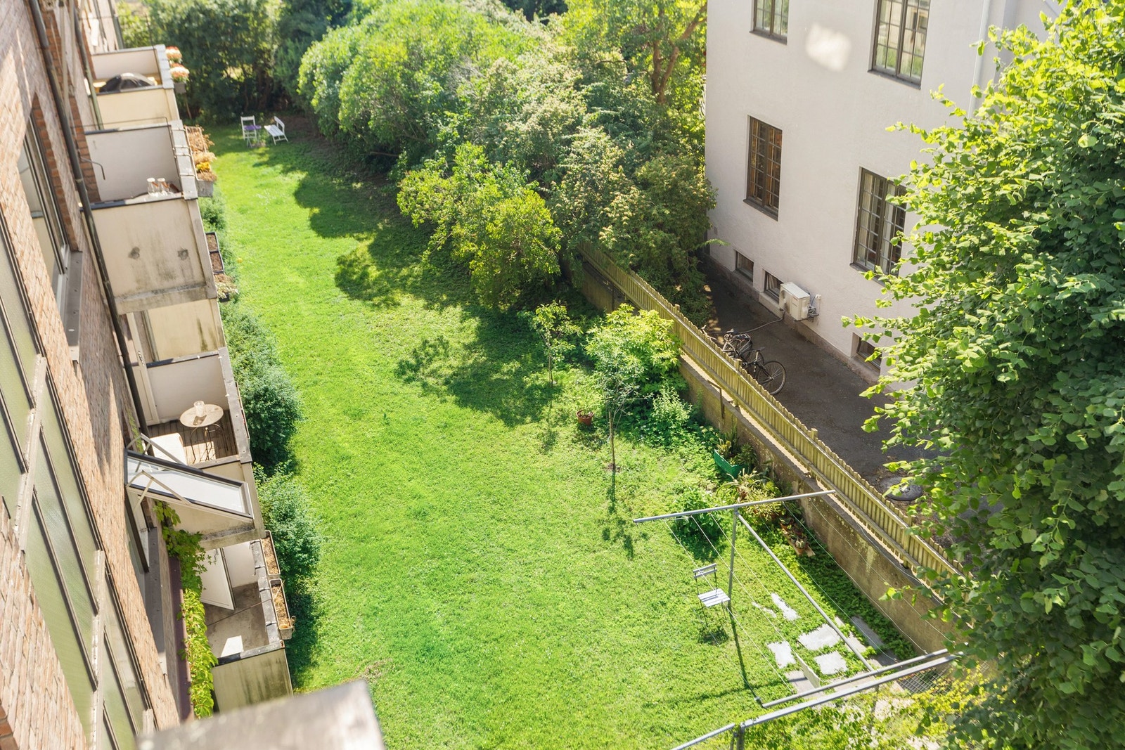 Utsyn fra balkong, mot fellesareal. Her kan du slappe av, spille bocha, badmington, fotball. Eller dyrke grønnsaker, plante bærbusker, epletrær med tillatelse fra styret. Hagen kan fritt brukes av beboerne! Galleribilde