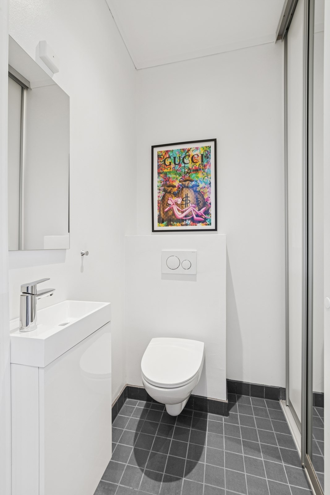 Praktisk toalettrom med wc og servantskap - bak skyvedøren er det plass til vaskemaskin og noe lagringsplass. Galleribilde