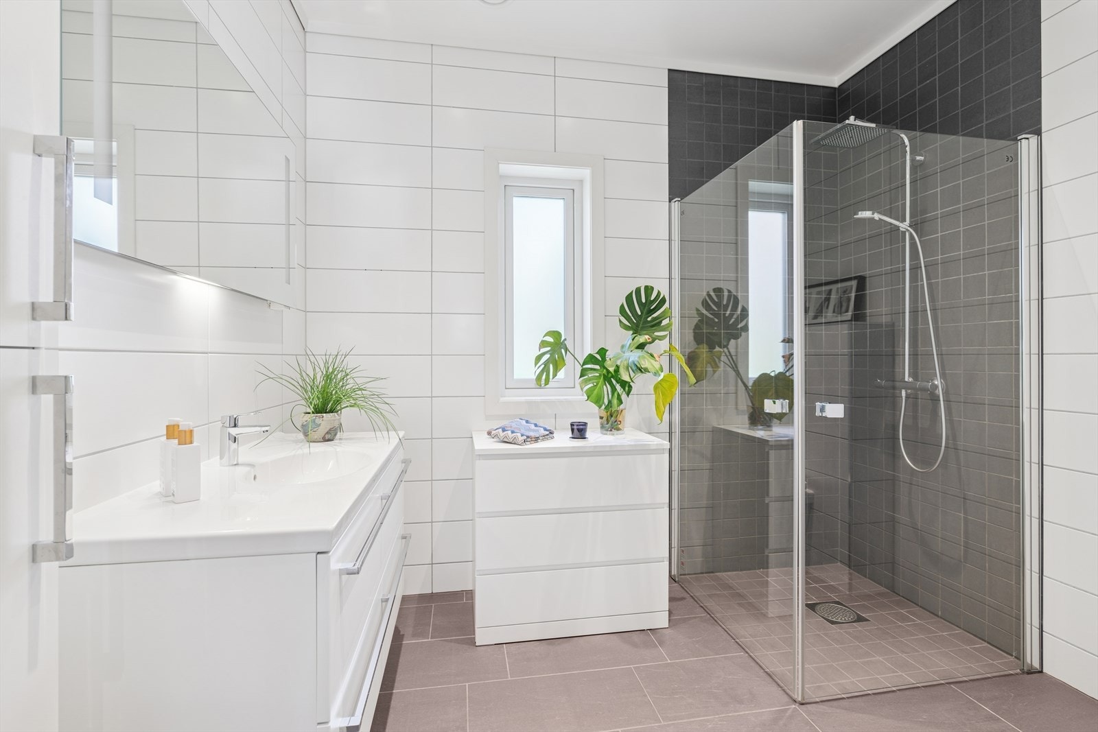 Stort og flislagt bad med dusjhjørne, veggmonter wc og romslig servantskap. Galleribilde