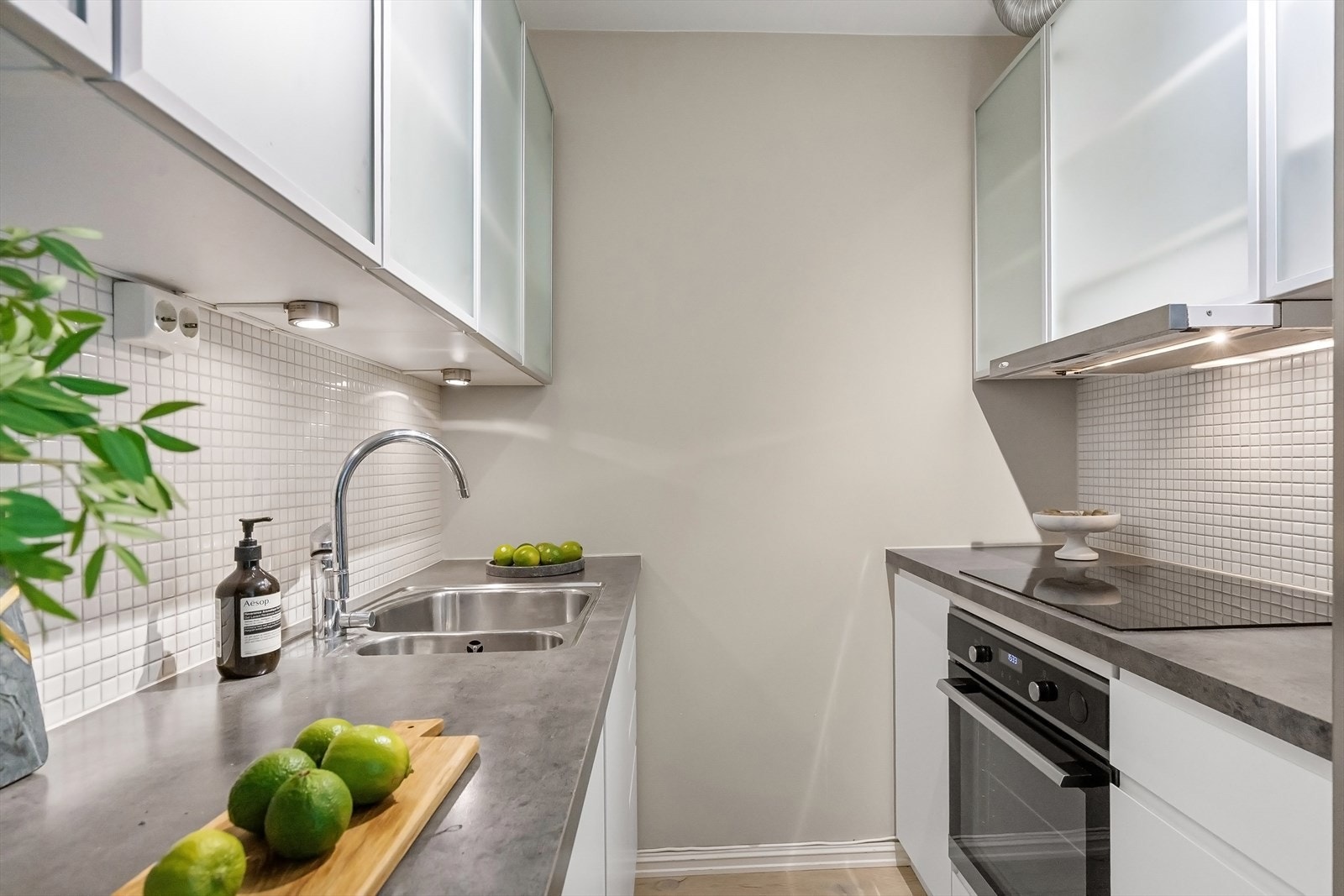 Lyst kjøkken med mosaikkfliser, godt med oppbevaringsplass og integrert induksjonstopp, stekeovn og oppvaskmaskin. Galleribilde