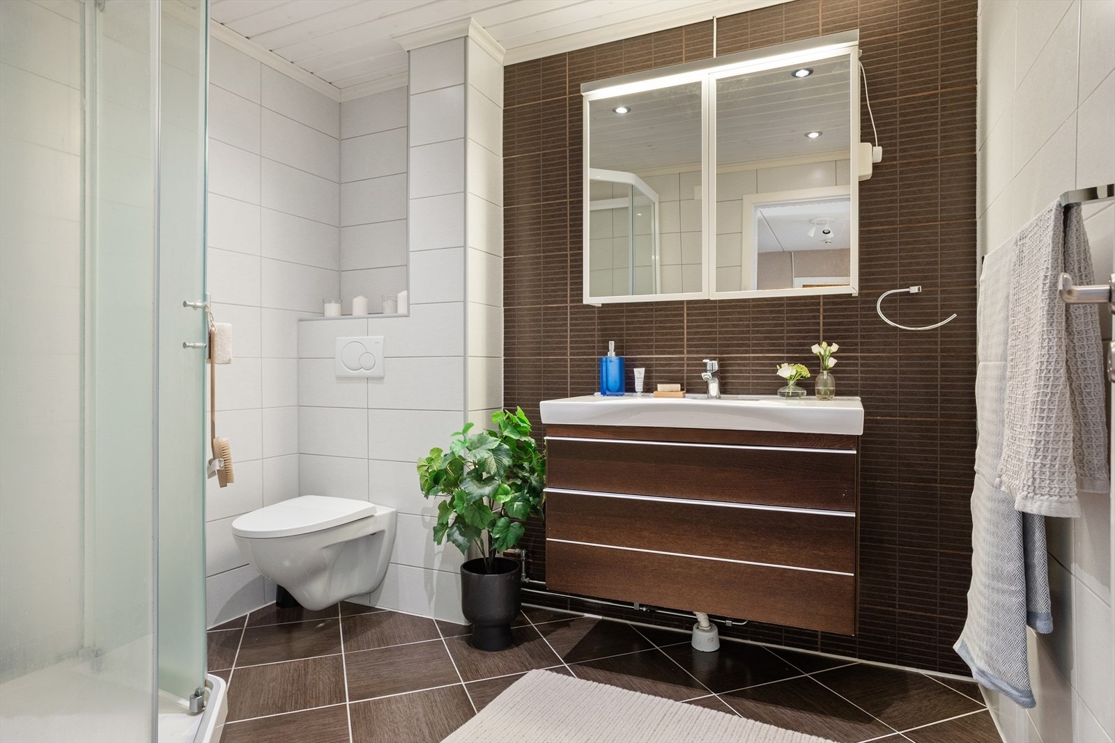 Badet er innredet med servant med oppbevaring, toalett og dusjkabinett Galleribilde