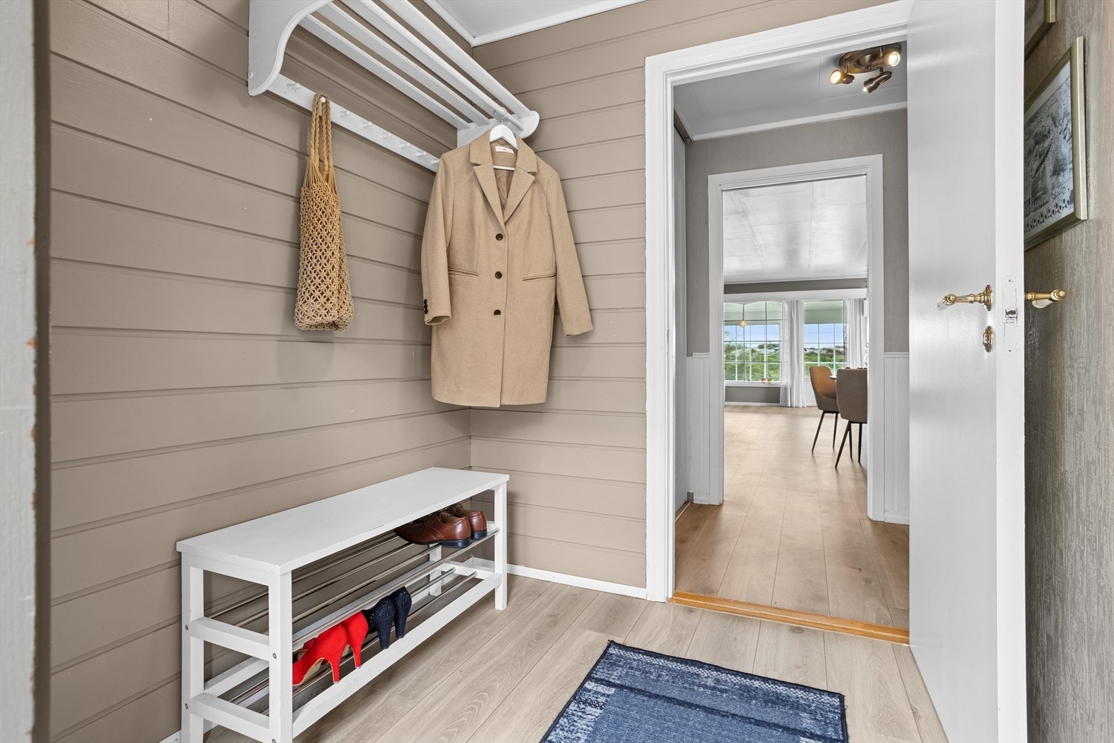 Man ønskes velkommen i et vindfang med plass til å henge fra seg yttertøy. Galleribilde