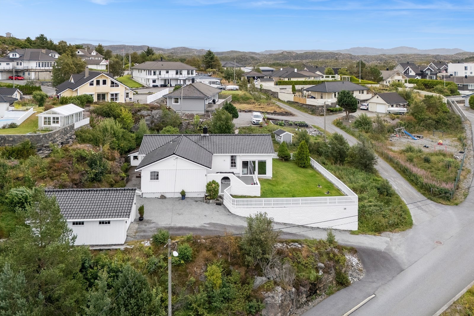 Det er en asfaltert adkomst mot garasjen og inngangspartiet. Galleribilde