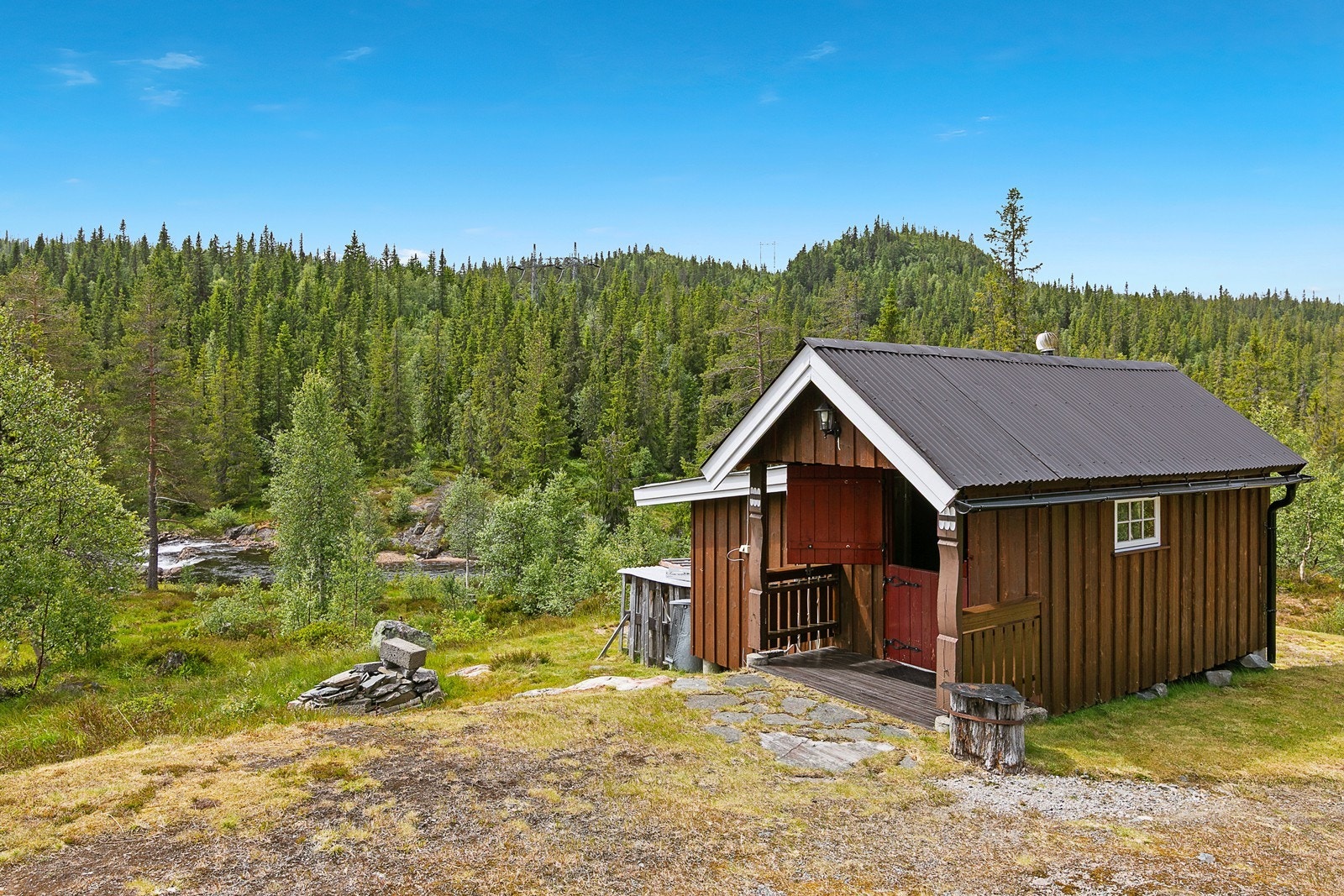 Uthuset er holdt i samme stil som hytta og har en rød, todelt dør. Galleribilde