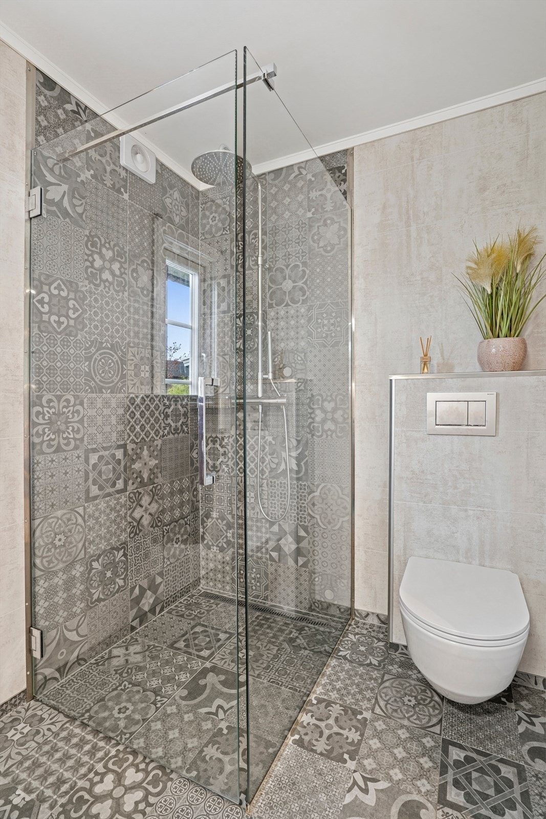 Badet er utstyrt med vegghengt toalett, flislagt dusjhjørne med glassvegger, samt baderomsinnredning med servant og speilskap. Galleribilde