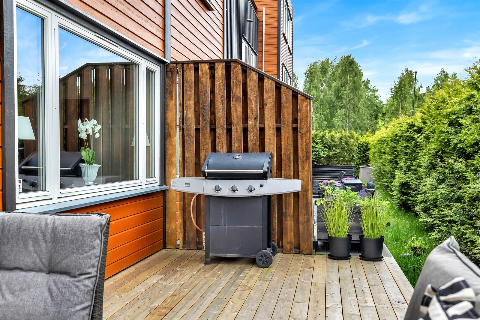 Uteplassen har skillevegg mot naboen og en stor hekk som skjermer for innsyn. Galleribilde