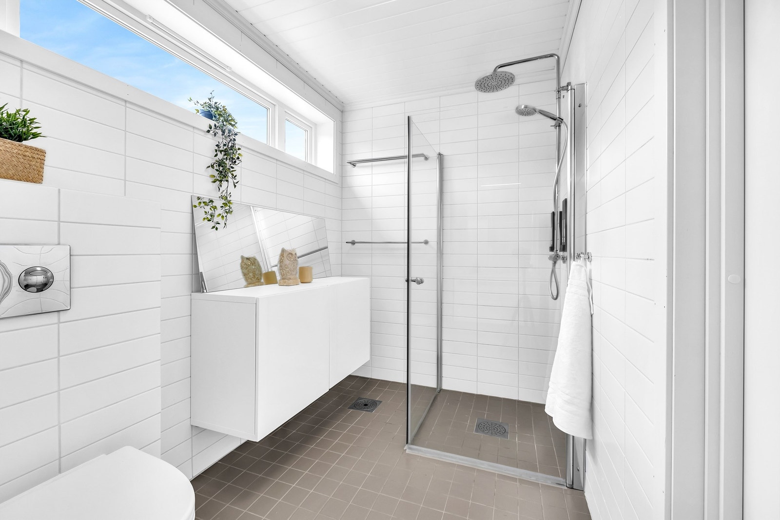 Rommet er innredet med vegghengt servantskap, vegghengt toalett, dusjhjørne og et praktisk oppbevaringsskap. Galleribilde