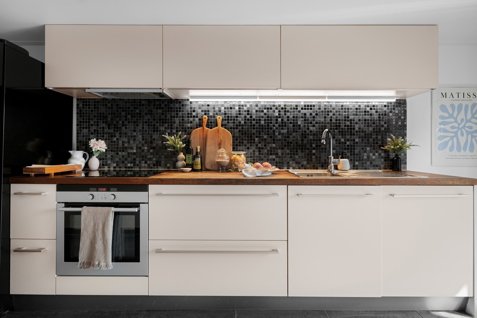 Heltre benkeplate, glatte fronter og integrerte hvitevarer som komfyr, platetopp, og oppvaskmaskin. Galleribilde