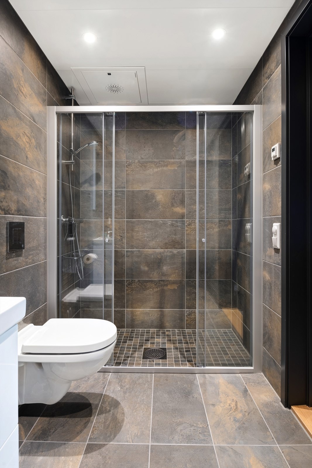 Badene er innredet med servant, vegghengt toalett og dusj Galleribilde