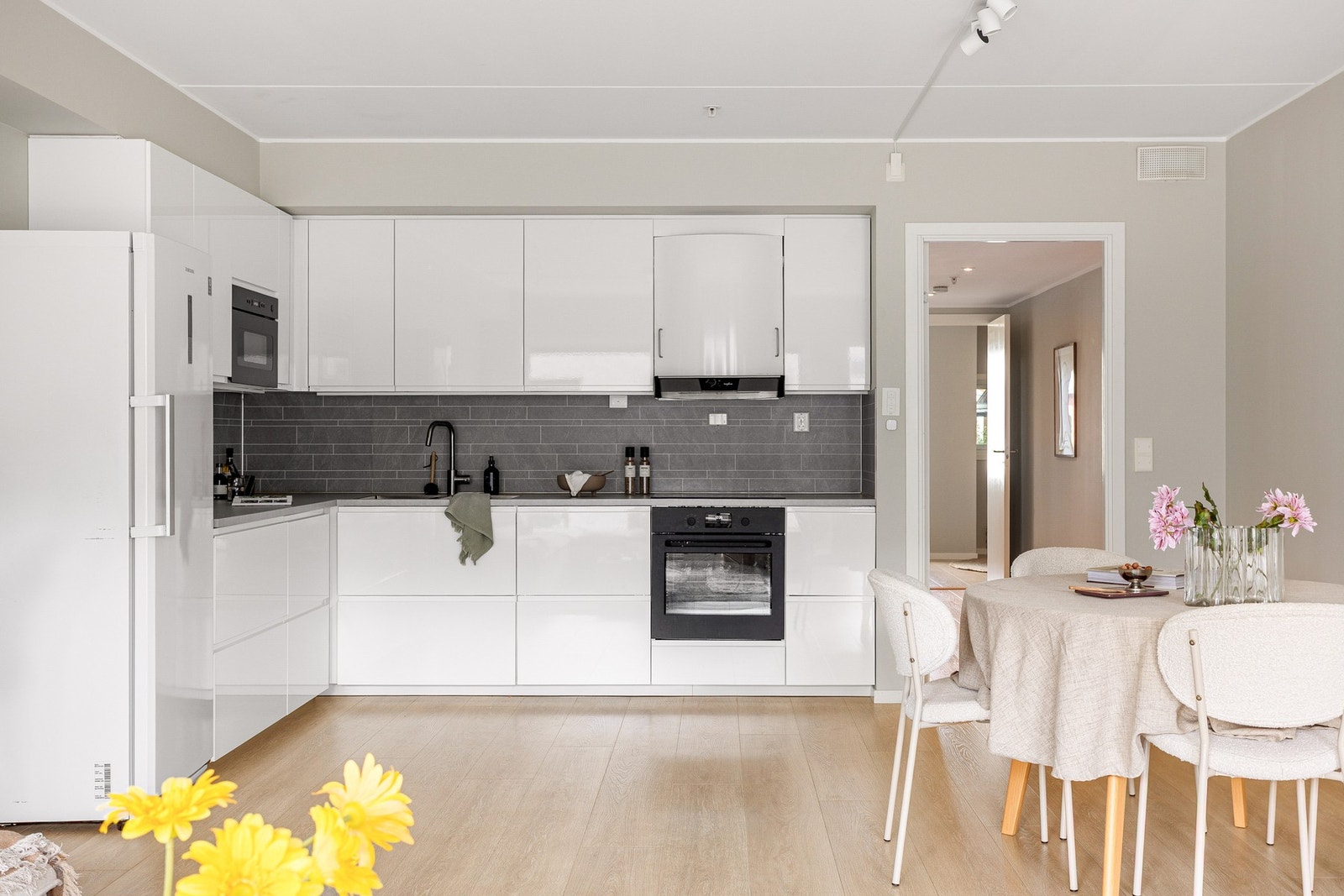 Her får du et pent og funksjonelt IKEA kjøkken fra 2022, som fremstår stilrent med slette fronter og benkeplate av laminat, samt laminert plate mellom kjøkkenbenk og overskap som gir et pent og lettstelt uttrykk. Galleribilde