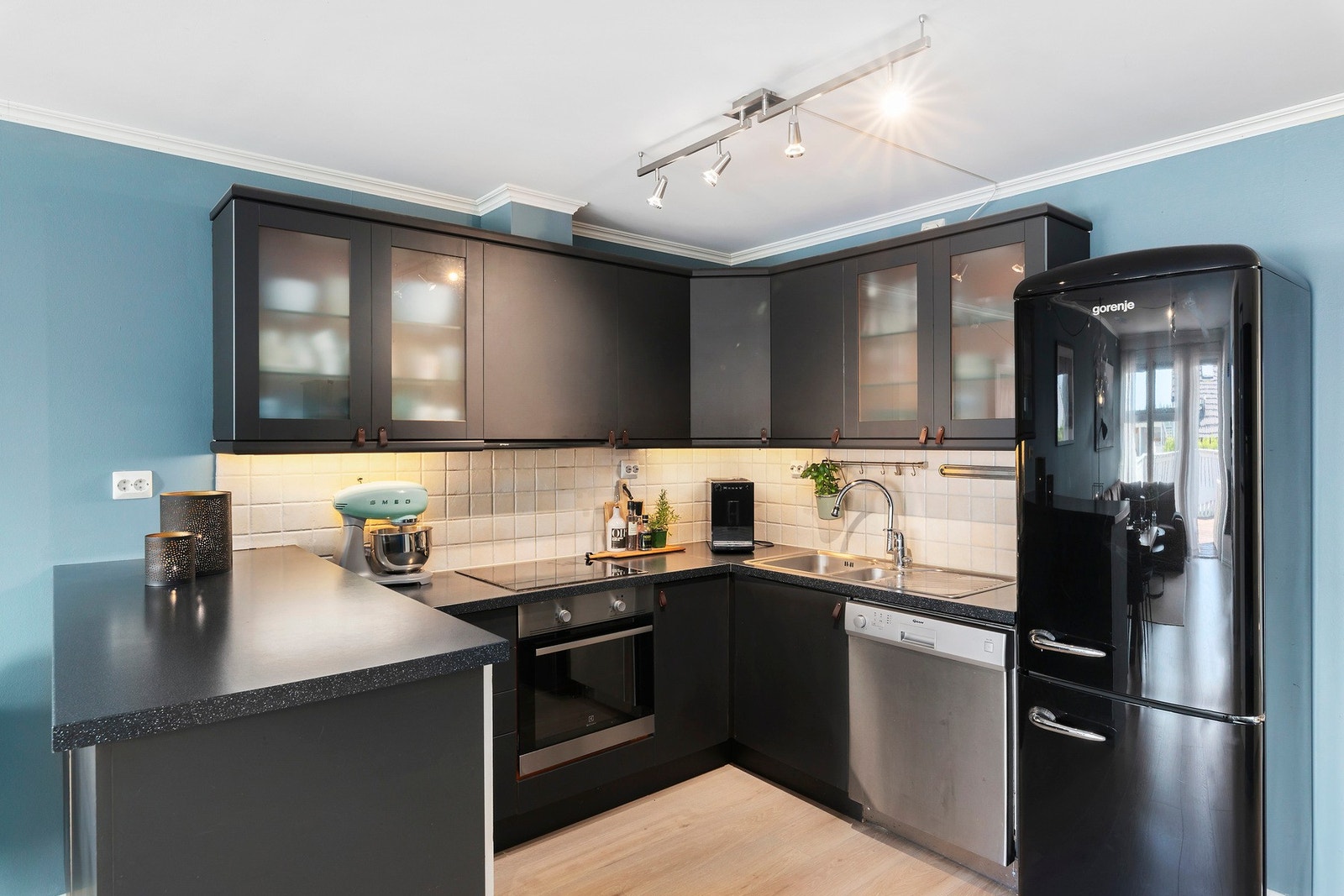 Innholdsrikt og praktisk kjøkken med malte fronter og fliser mellom overskap og benkeplate. Galleribilde