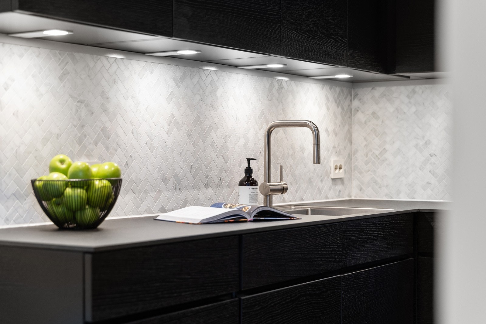 Det inneholder blant annet en underlimt kjøkkenvask, integrerte hvitevarer, oppvaskmaskin, og ventilator med kullfilter Galleribilde