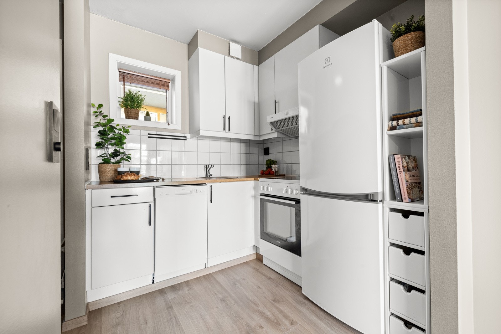 Lys innredning, laminat benkeplate og frittstående hvitevarer. Galleribilde
