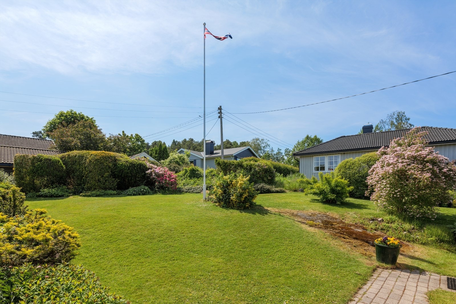 Hagen er flott opparbeidet med flaggstang, prydbusker, trær og flerårige planter. Hagen er også utstyrt med robotgressklipper som medfølger salget. Galleribilde