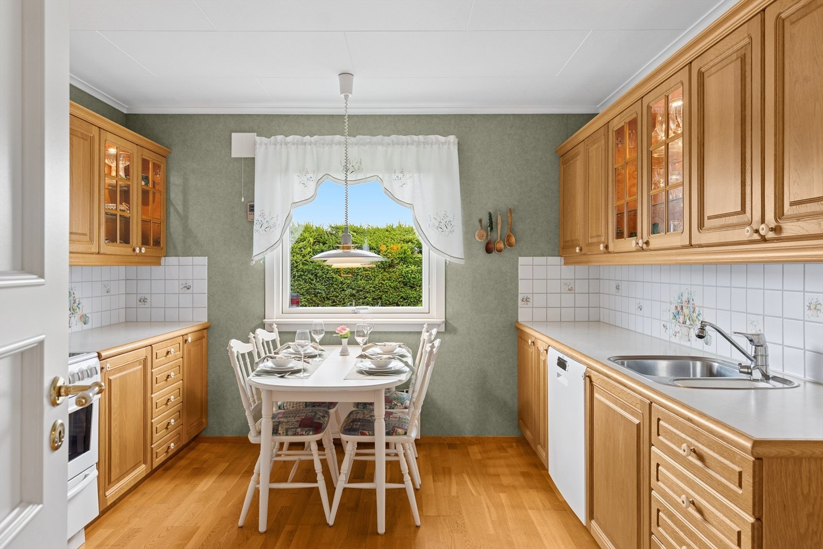 Kjøkkenet er levert av Huseby og ble satt inn i 1996. Et stort og godt kjøkken med profilerte heltre eike fronter og hvit benkeplate i laminat. Her har man godt med skap- og skuffeplass, samt gode arbeidsflater på benk. Galleribilde