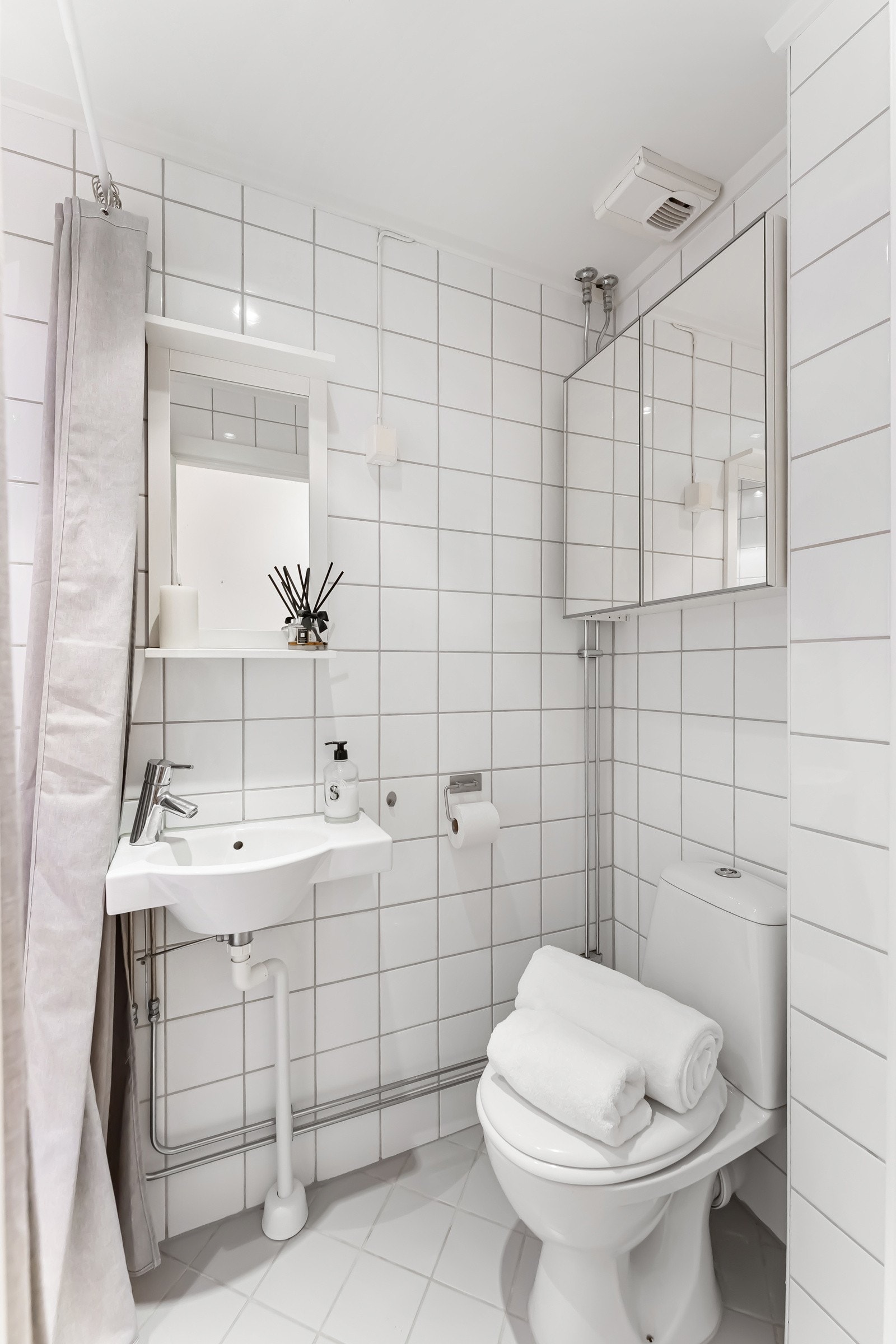 Lyst flislagt baderom med varmekabler og downlights. Badet er utstyrt med servant, speilskap, toalett og dusj i hjørnet Galleribilde