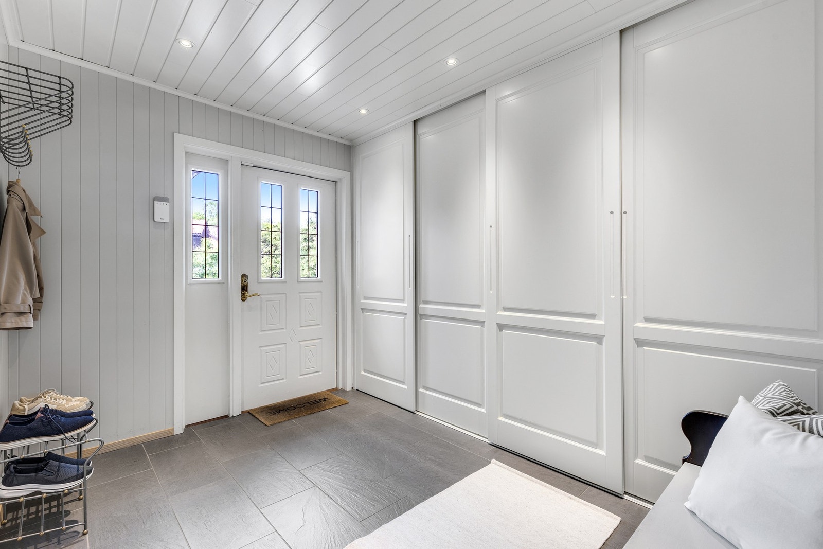 Lys og fin entré med enkel klesoppheng og oppbevaring i skyvedørsgarderobe. Galleribilde