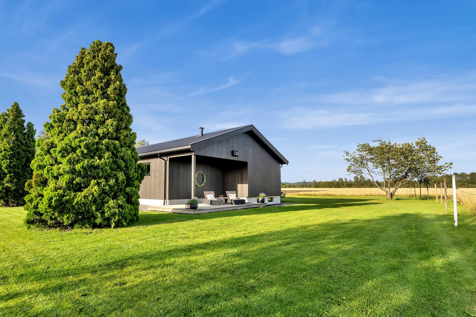Stor gressplen og egen terrasse på baksiden av boligen Galleribilde