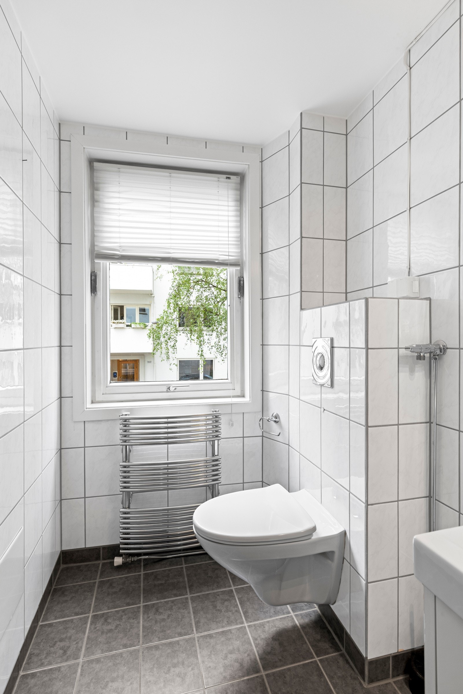 Badet har flislagt gulv med varmekabler og flis på veggeer. Det er ventilasjon via mekanisk vifte og lufting under døren. Galleribilde