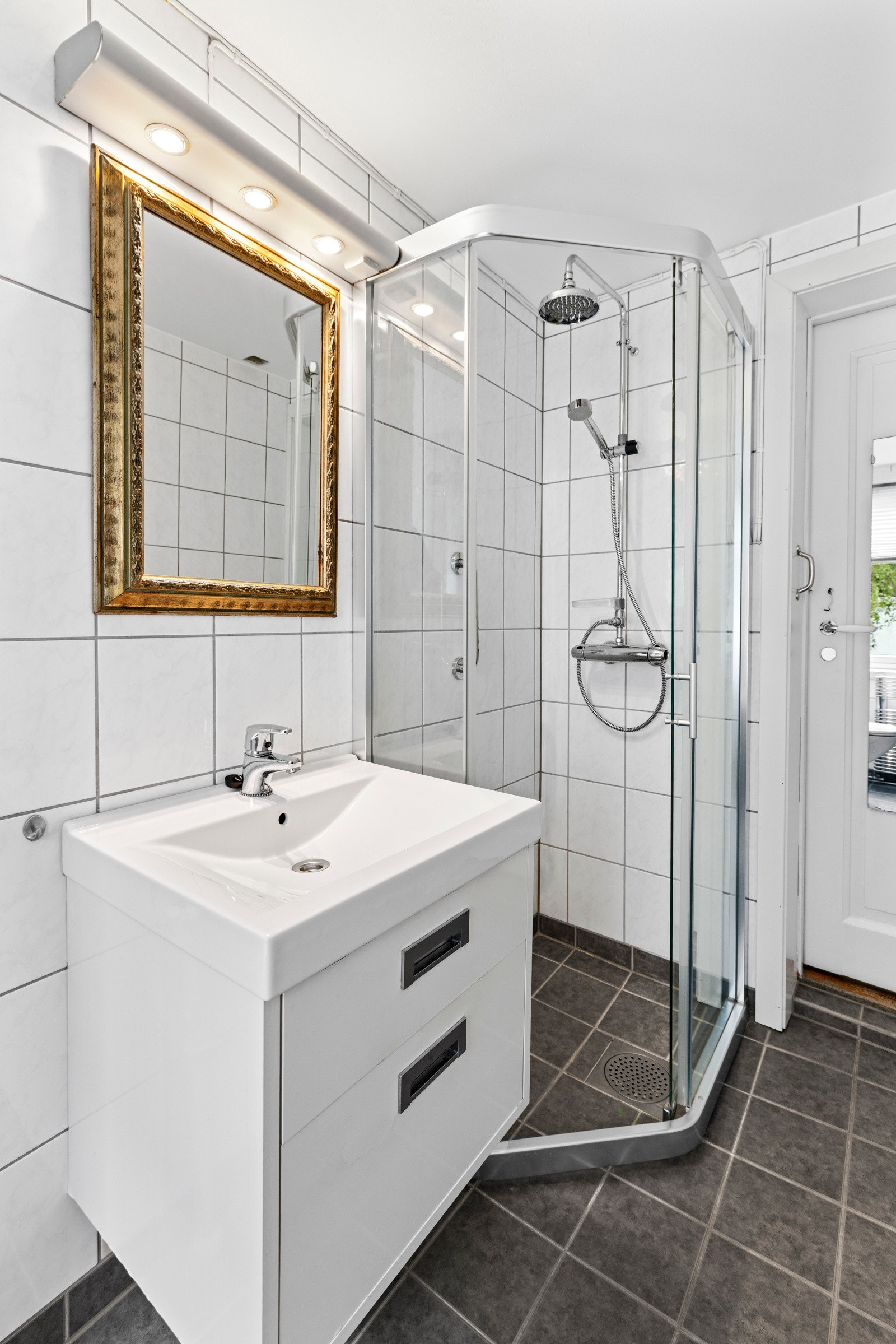 Rommet er utstyrt med et dusjhjørne, vegghengt toalett, speil og en servant med underskap som gir noe oppbevaringsplass. Galleribilde