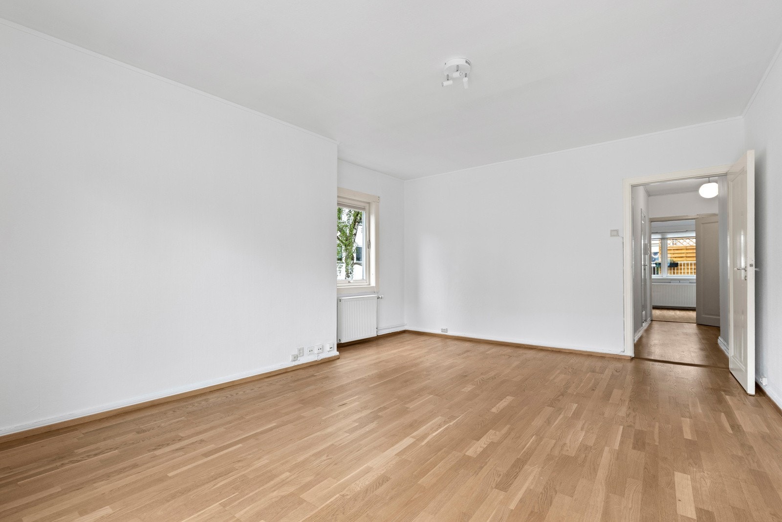 Her kan du enkelt skape både en sofakrok og en spisestuesone. Gulvet er dekket av parkett, mens veggene er malt i lyse toner som bidrar til et lyst og praktisk oppholdsrom. Galleribilde