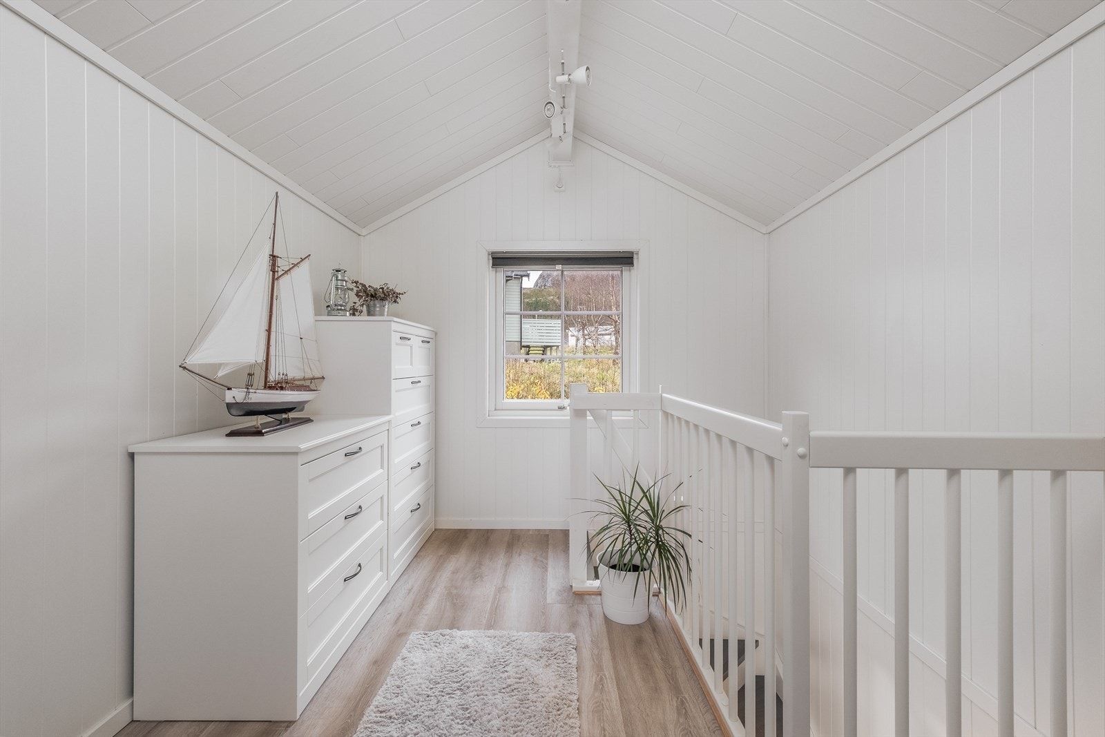 Alle soverommene er tilknyttet en lys gang med hvitmalt rekkverk mot trappeløpet. Galleribilde