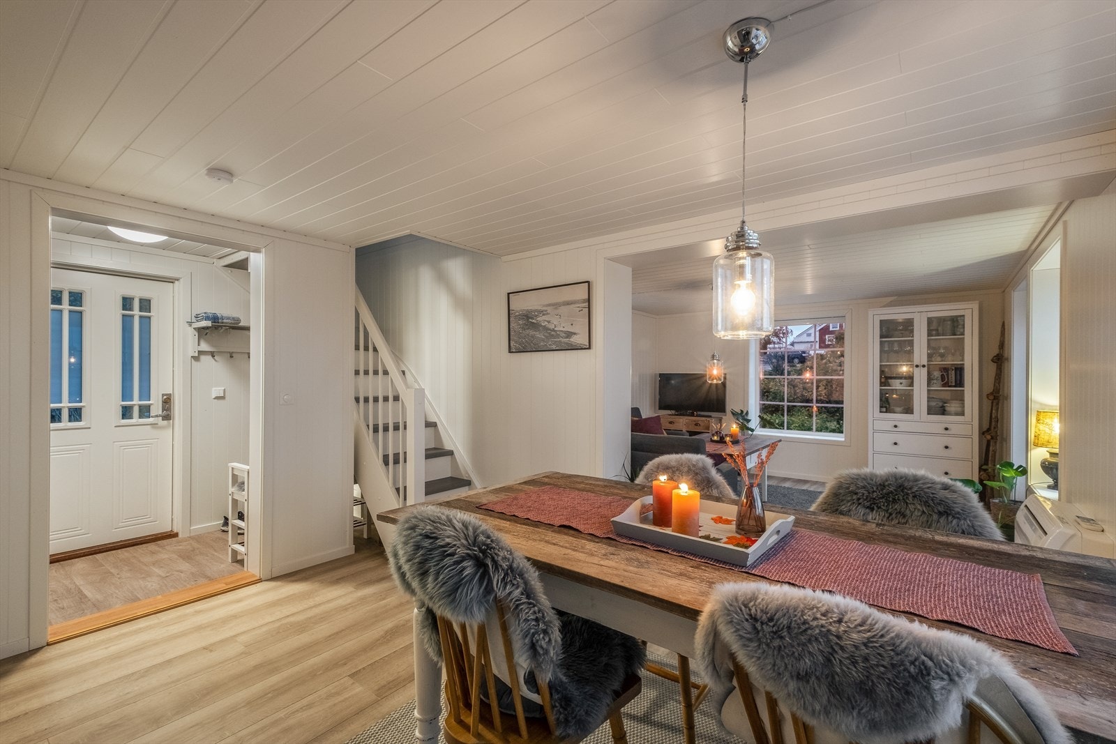 Entreen har åpen garderobeløsning og åpen gjennomgang til stuen, hvor du finner trappen til etasjen over. Galleribilde