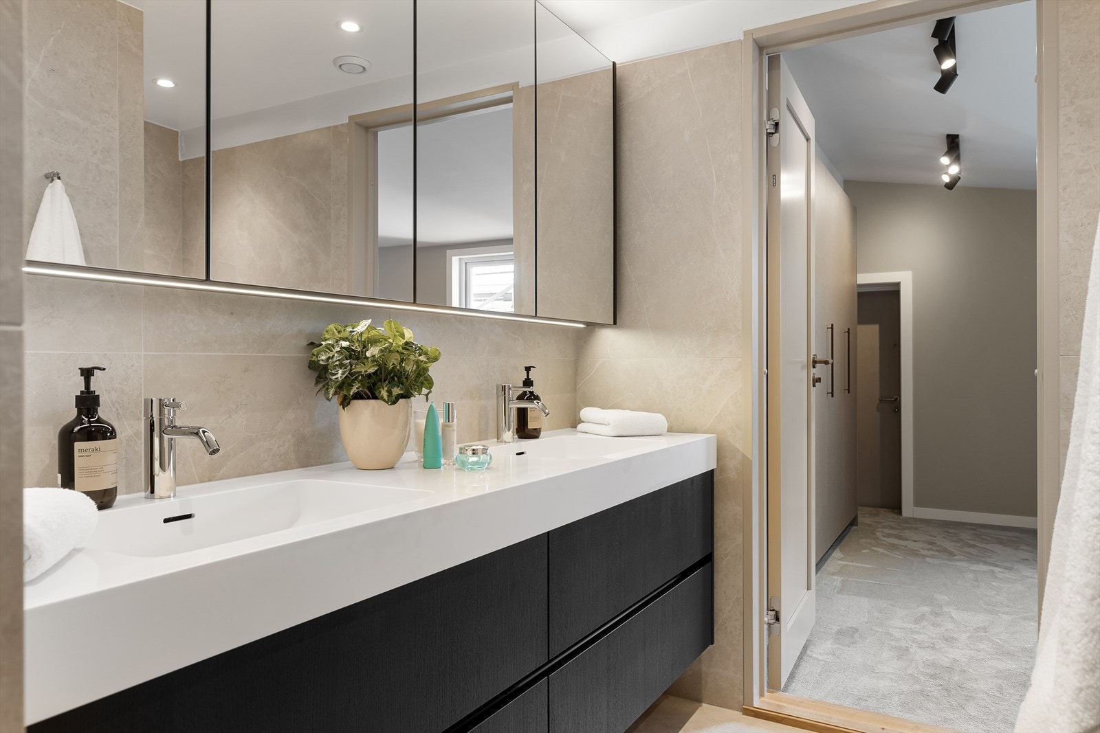 Innredning med skuffer og 2 nedfelte servanter, bredt veggmontert skap med speilfronter og veggmontert toalett. Nye varmekabler. Direkte adkomst fra hovedsoverom. Galleribilde