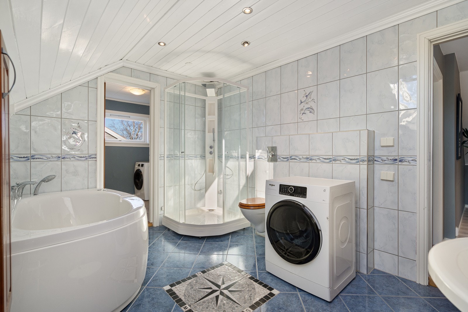 Romslig, flislagt bad med dusj, badekar, servant og toalett. Galleribilde