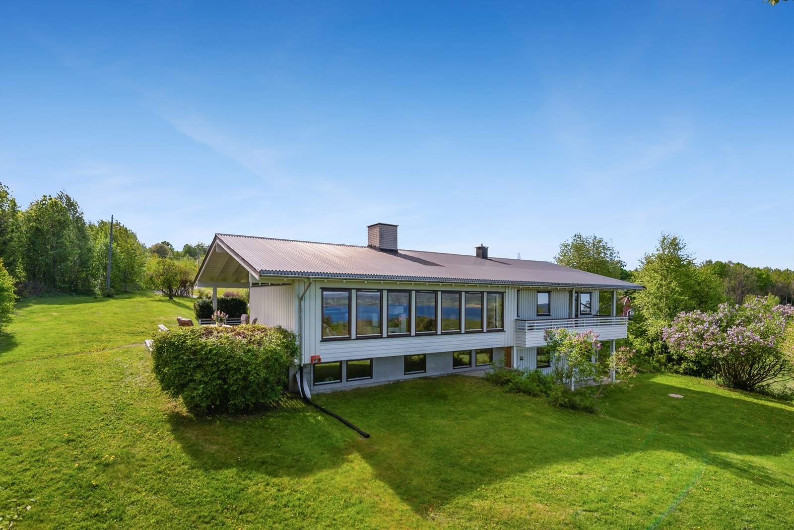 Tomten er pent anlagt med gressplen og variert beplantning. Galleribilde